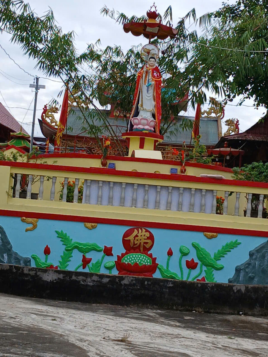 Quan Am statue on a lotus-decorated wall